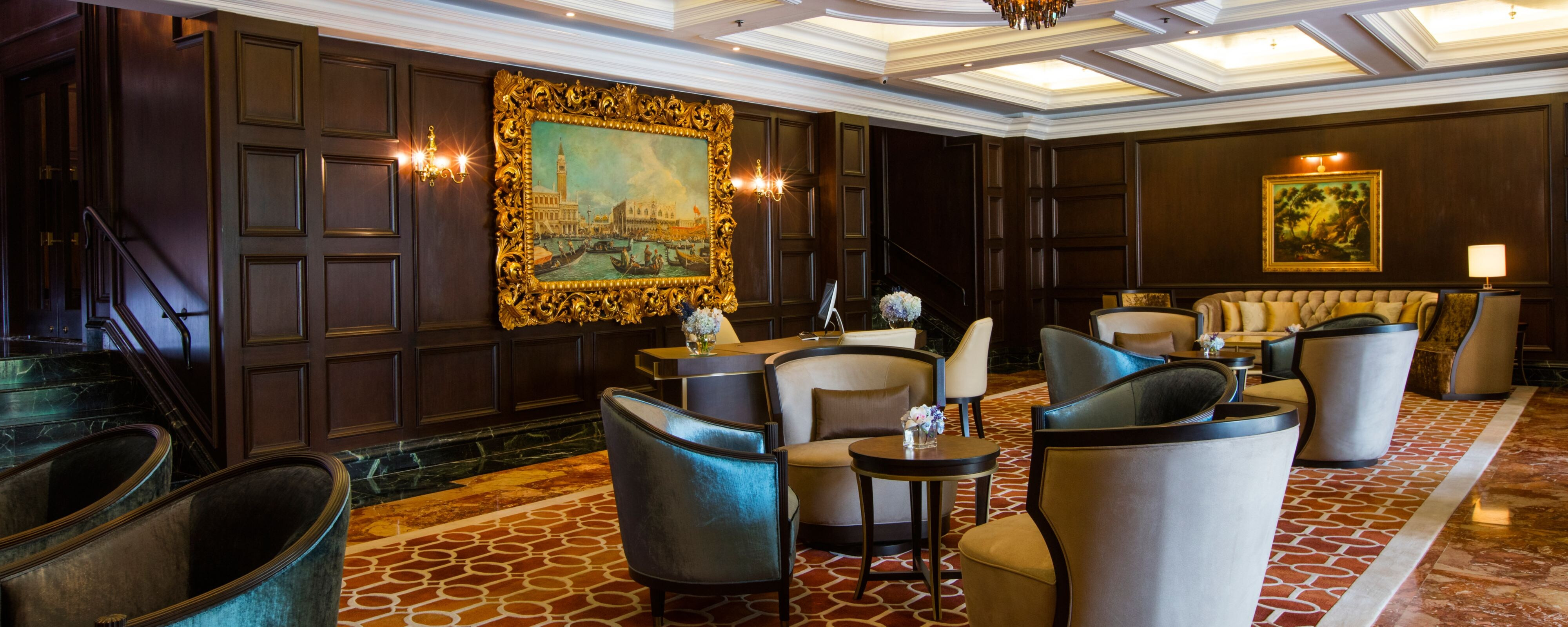 Tầng Club Lounge với tường ốp gỗ tối màu, tranh ảnh đóng khung mạ vàng và trần nhà màu trắng dầm vuông